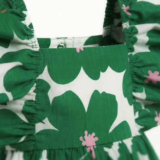 Close-up of a green and white patterned garment with ruffled trim and small pink floral accents.