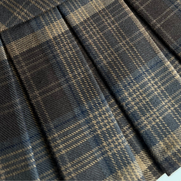 Close-up of a pleated skirt in a dark navy blue and brown plaid pattern.