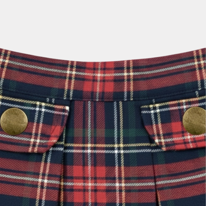 Close-up of a plaid fabric with brass buttons on a light gray background