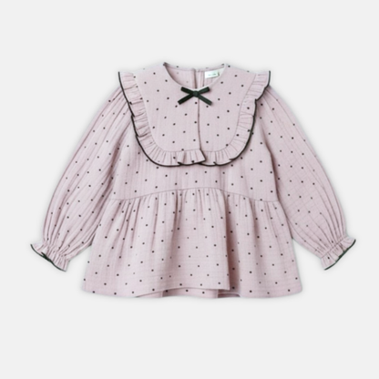 Pink polka dot dress with a ruffled bib on a white background