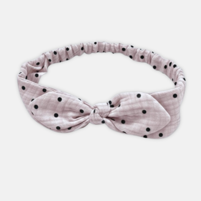 Pink muslin headband with black polka dots on a white background
