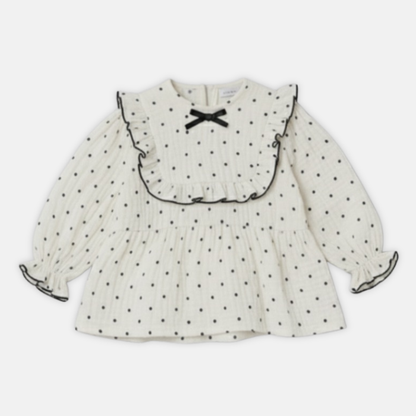 Offwhite muslin dress with black polka dots and a bow on a white background
