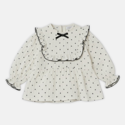Offwhite muslin dress with black polka dots and a bow on a white background