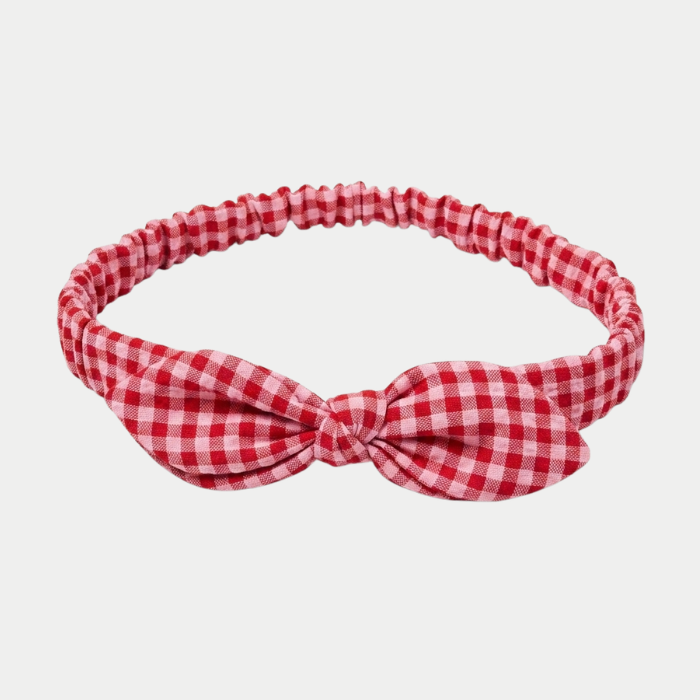 A red and pink seersucker checkered headband , photographed on a light gray background.