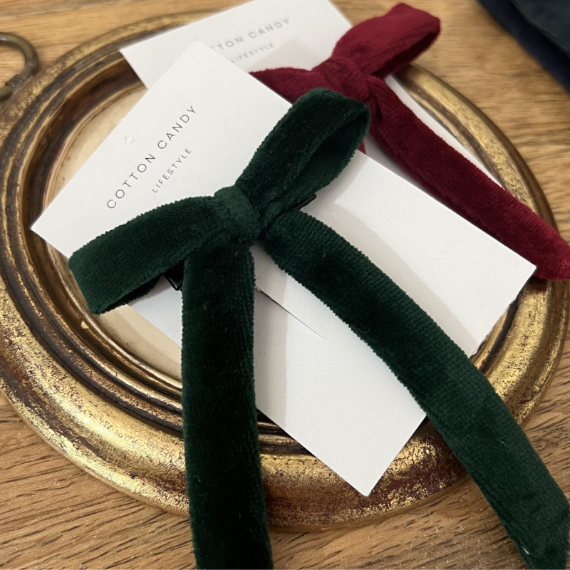 Two boxes tied with green and red velvet ribbons on a gold tray.